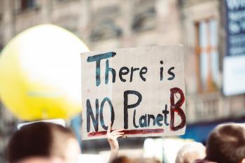 Image: protestor holding sign that says "There is no Planet B." Title: What Do Corporate Commitments for Climate Week Really Mean?