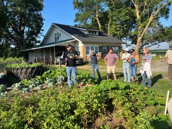 seven people standing outside a garden in the morning sunlight